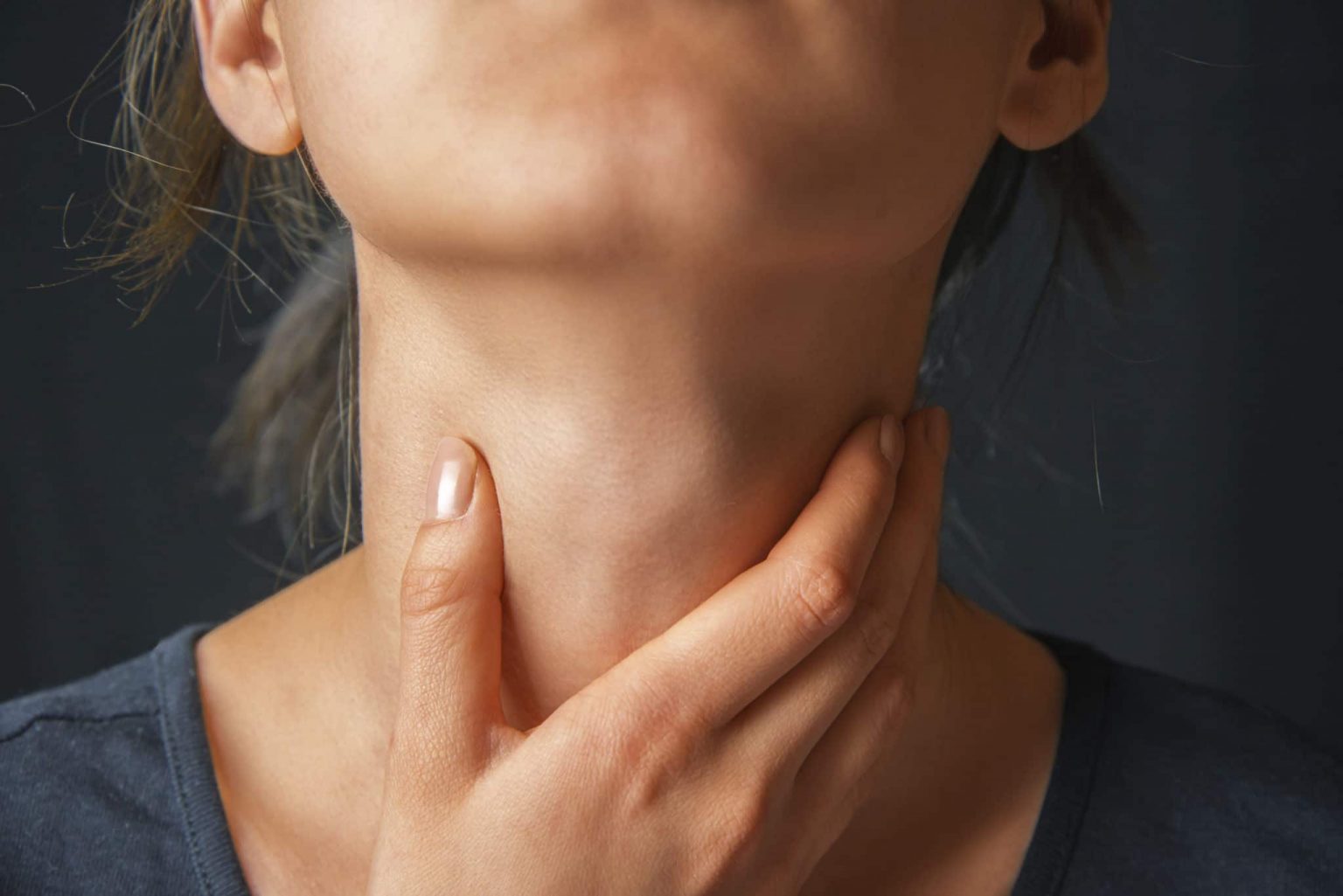Woman with hand on throat assessing her swallowing disorder.
